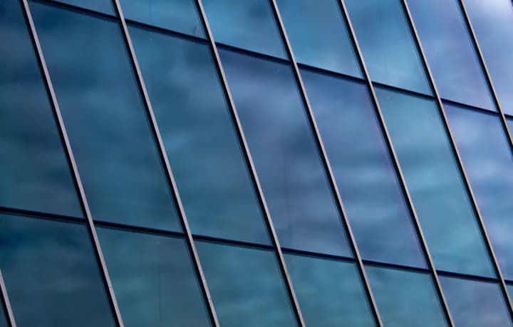 A glass curtain wall, its panes ruled into an even grid.