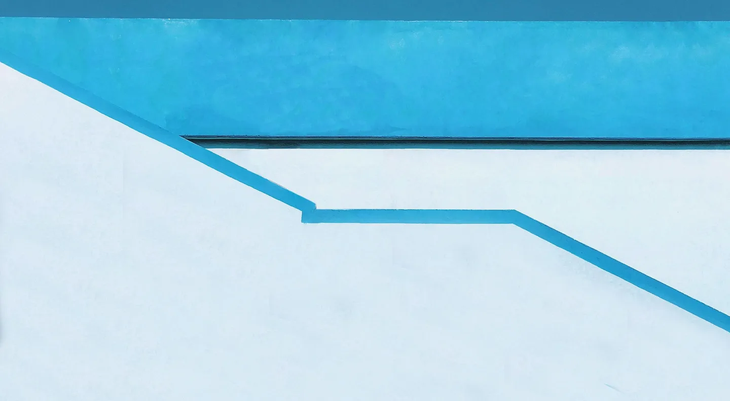 Blue painted lines stepping down a white wall.